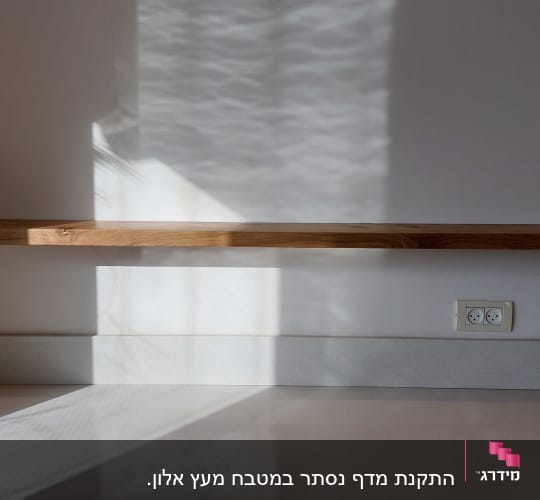 מדף עץ מותקן על קיר לבן